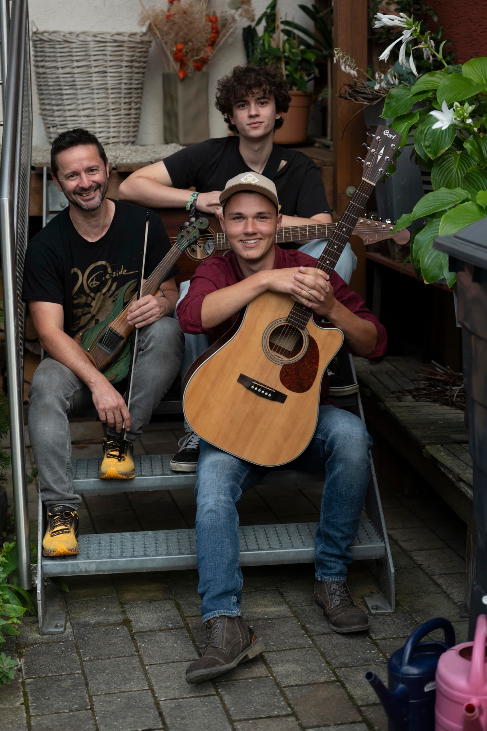 Florian, Rainer und Leander mit Gitarren auf einer Treppe